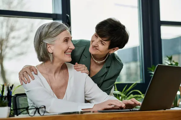 Two women engage with a laptop together. — Stock Photo