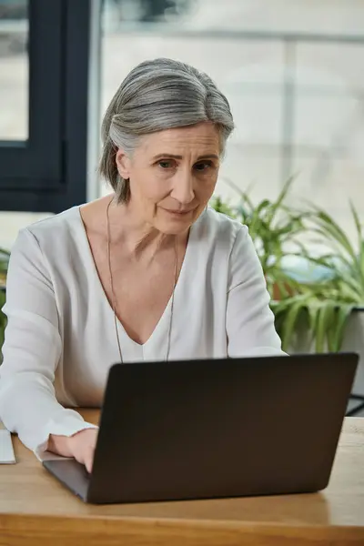 A woman sitting at a laptop, fully focused on work. — Stock Photo