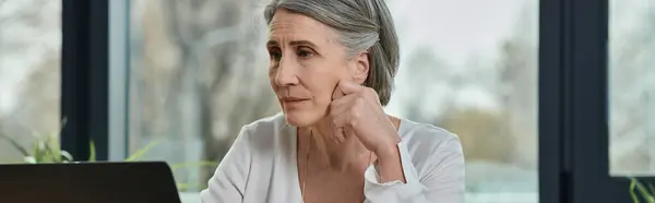 Woman engrossed in work on laptop in modern office setting. — Stock Photo