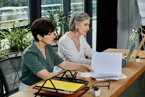 Two women engrossed in work on a laptop at a table. — Stock Photo