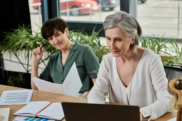 Zwei Frauen arbeiten an einem Laptop an einem Tisch. — Stockfoto