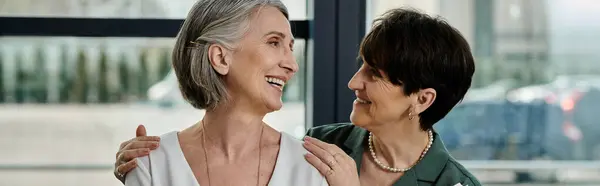 Dos mujeres están de pie junto a la ventana, brillando en luz natural. — Stock Photo