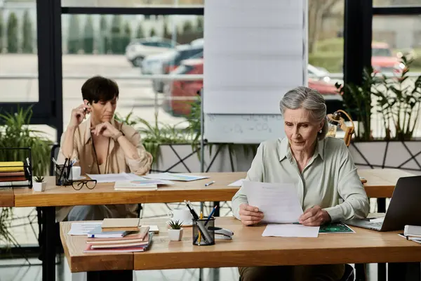 Two women focused on work at a table. — Stock Photo