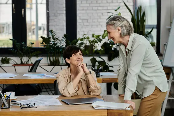 A mature beautiful lesbian couple collaborating at a table. — Stock Photo