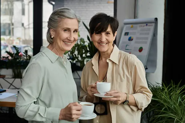 Two elegant women holding cups, enjoying a moment together. — Stock Photo