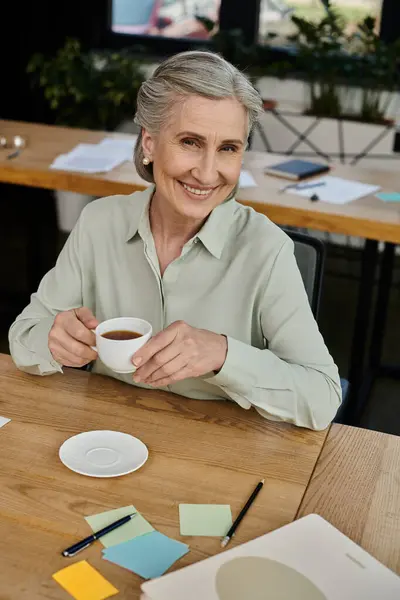 Uma mulher saboreia uma xícara de café em uma mesa. — Fotografia de Stock