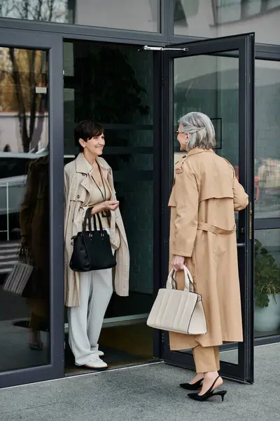 Two mature, beautiful women standing outside a building, possibly their office. — Stock Photo