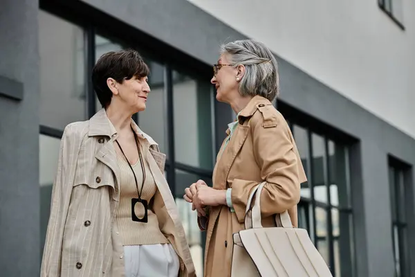 Two elegant women engaged in conversation outside a modern building. — Stock Photo