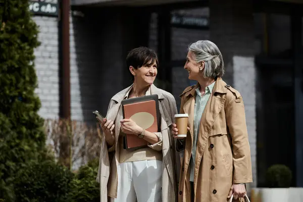 Due donne eleganti stanno l'una accanto all'altra di fronte a un grande edificio. — Foto stock