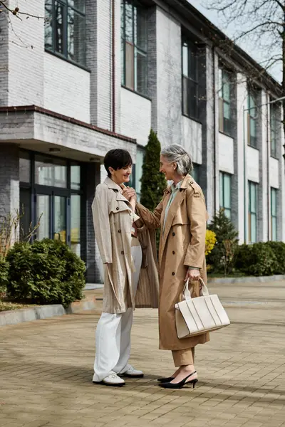 Two sophisticated women stand in awe before a grand building. — Stock Photo
