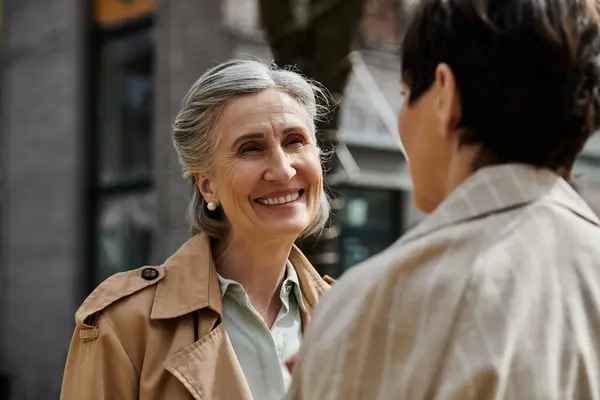 Two women smiling in stylish trench coats. — Stock Photo