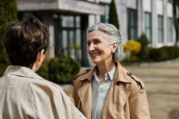 Two women converse in front of building. — Stock Photo