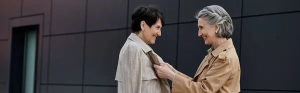 A mature and beautiful lesbian couple standing together by a building on their way to the office. — Stock Photo