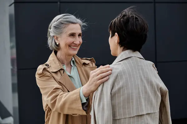 Mature, beautiful lesbian couple walking to office in trench coats. — Stock Photo