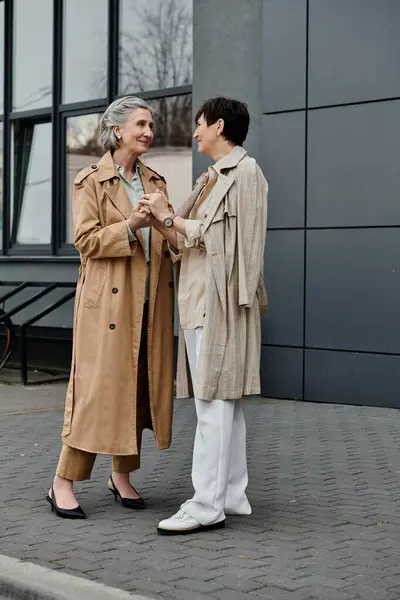 Mature lesbian couple enjoying a stroll in front of a modern building. — Stock Photo