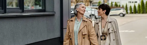 Hermosa pareja lesbiana caminando casualmente por una calle urbana. - foto de stock