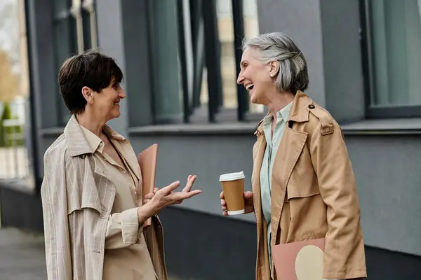 Due donne impegnate in una conversazione mentre tengono tazze di caffè. — Foto stock