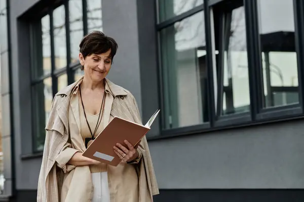 A woman leisurely walks down a street, holding a book. — Stock Photo