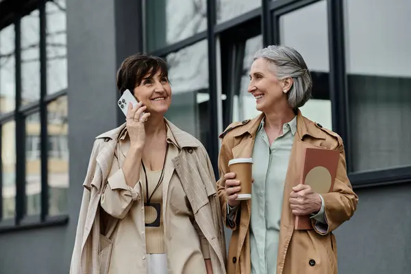 Two women walking, engaged in conversation on cell phone. — Stock Photo