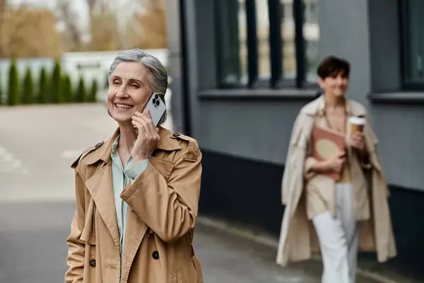Женщина болтает по телефону, прогуливаясь по улице со своим партнером. — стоковое фото
