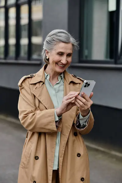 Una donna in impermeabile che usa un cellulare. — Foto stock