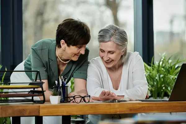 Two women engrossed in laptop work together. — Stock Photo