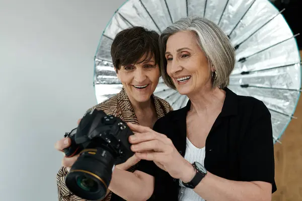 A woman poses with a camera, clicking a self-portrait in a photo studio, capturing her individuality and expression. — Stock Photo