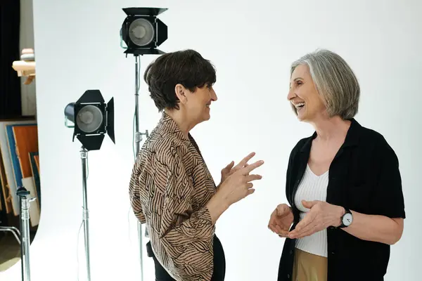 A middle aged lesbian couple engage in conversation in a photo studio — Stock Photo