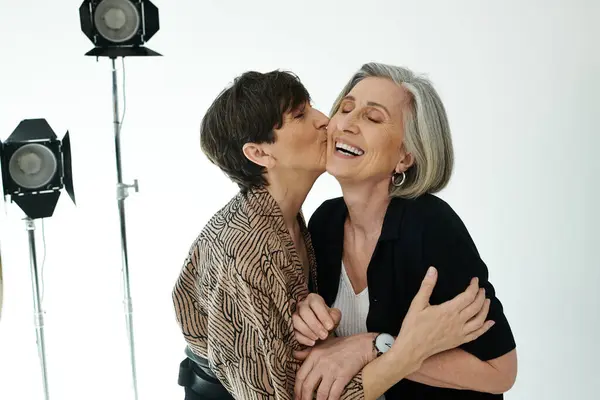 Middle-aged lesbian couple kissing in a photo studio — Stock Photo