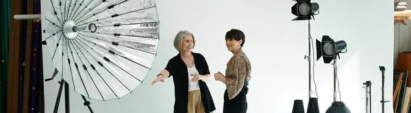 Middle-aged lesbian couple in a studio, standing in front of a wall. — Stock Photo