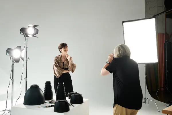 Couple lesbien d'âge moyen dans un studio photo ; une femme claquant une photo de son partenaire devant la caméra. — Photo de stock