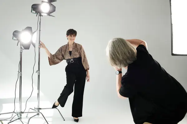 A middle-aged woman poses in a burst of light with a camera-wielding photographer, showcasing the art of photography. — Photo de stock