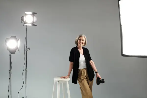 Middle aged photographer with digital camera striking a pose in photo studio — Stock Photo