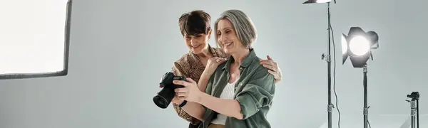 A mature age woman holds a camera while her partner checking photo — Stock Photo