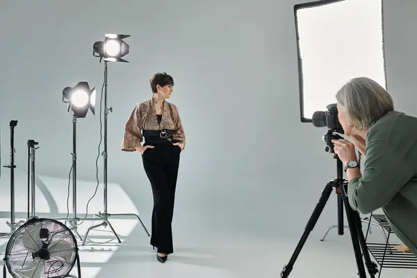 Middle-aged lesbian couple in a vibrant studio setting - one photographer with camera, the other posing as a model. — Stock Photo