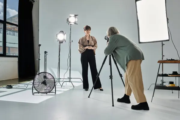 Лесбійська пара середнього віку в фотостудії; одна жінка з фотоапаратом, інша позує як модель. — стокове фото
