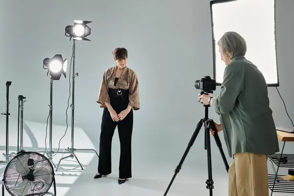 Фотограф середнього віку захоплює свого партнера, позуючи в фотостудії. — стокове фото