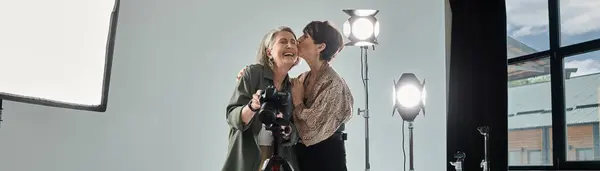 A middle-aged lesbian couple kissing near camera in a photo studio — Stock Photo