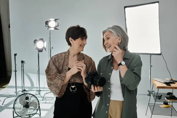 Лесбійська пара середнього віку об'єдналася в фотостудії, спілкуючись біля камери — стокове фото