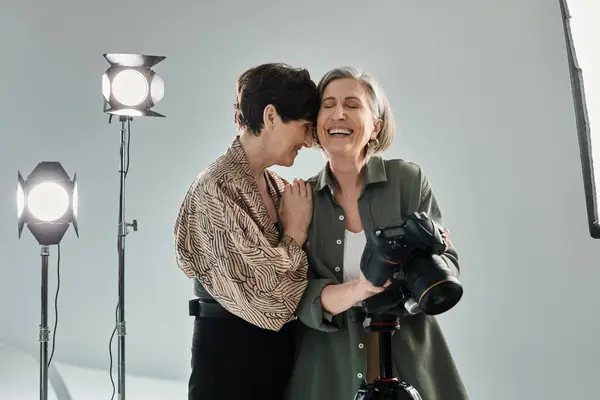 Лесбийская пара средних лет в фотостудии, смеющаяся и обнимающаяся — стоковое фото