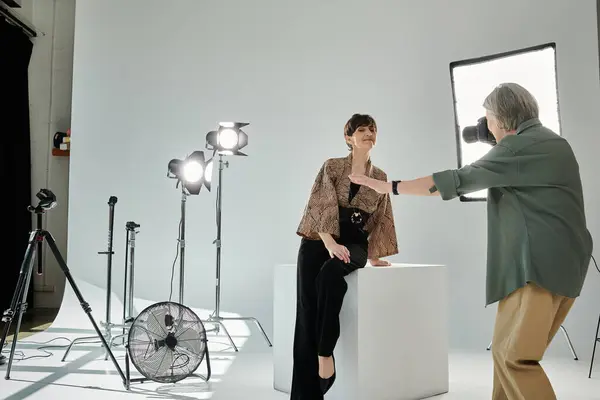 Um casal lésbico de meia-idade, um com uma câmera, fica na frente de um modelo em um estúdio de fotos. — Stock Photo