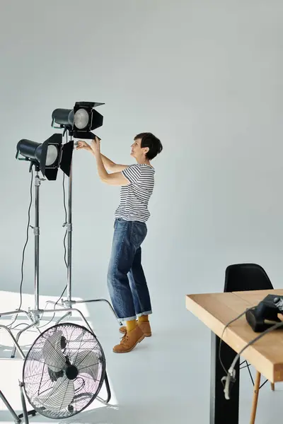 A woman creatively captures the world from a unique perspective, standing on a chair and adjusting softbox — Stock Photo