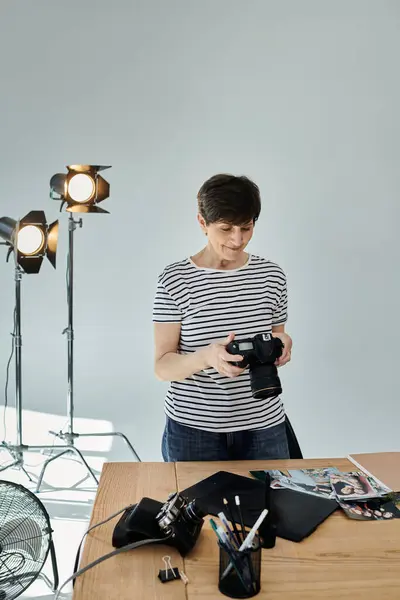 A woman adjusting settings on a camera for a professional photoshoot. — Photo de stock