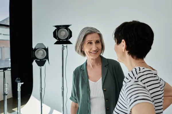 Two middle-aged women engage in a lively discussion at a professional photo studio. — Stock Photo