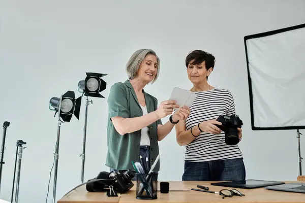 Two middle aged women stand confidently together in a modern photo studio — Stock Photo