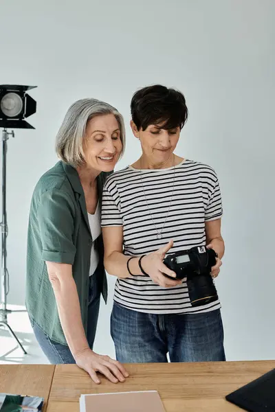 Two middle-aged women looking at professional camera in a modern photo studio setting. — Stock Photo