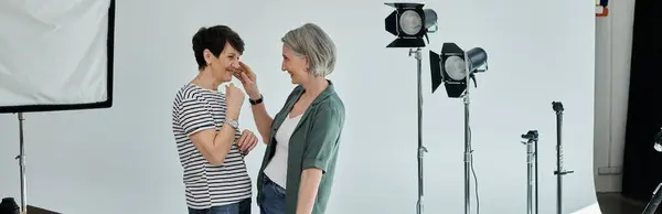A middle-aged lesbian couple confidently poses for a camera in a modern photo studio. — Stock Photo