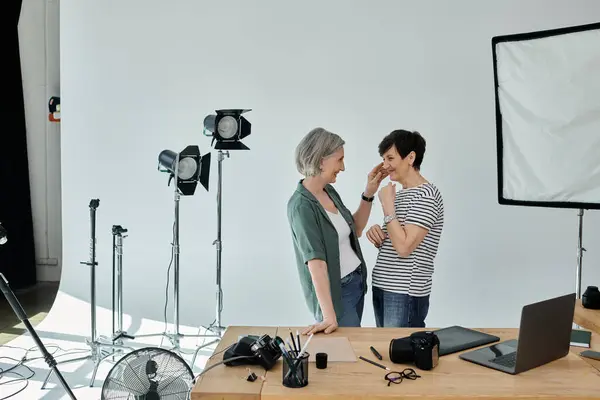 A middle-aged lesbian couple poses confidently in a professional photo studio while the camera captures their connection. — Stock Photo