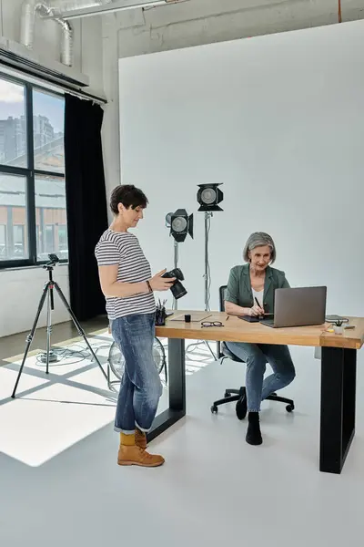 Collègues collaborant devant un ordinateur portable dans un studio photo professionnel. — Photo de stock