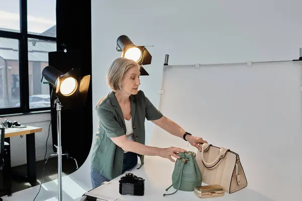 Un photographe tient avec confiance un sac à main devant un appareil photo dans un studio photo professionnel moderne. — Photo de stock